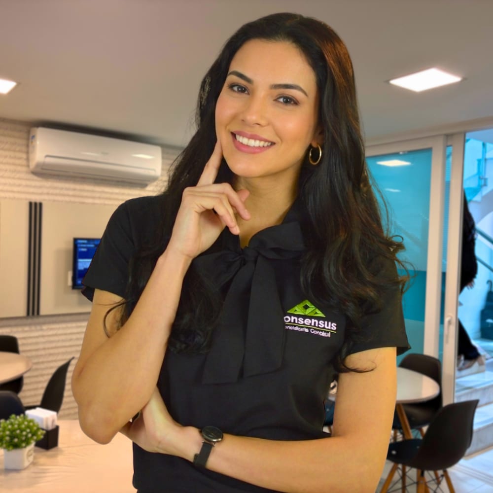 Moça sorrindo com um dedo na bochecha, com a cafeteria ao fundo.